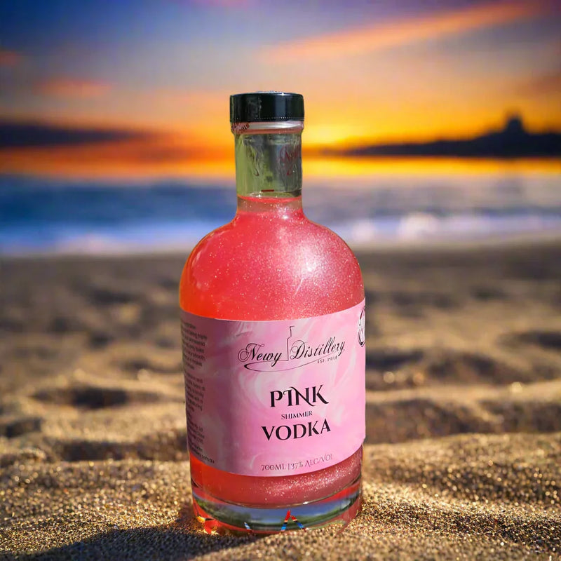 Bottle of pink vodka on grass with plants in the background