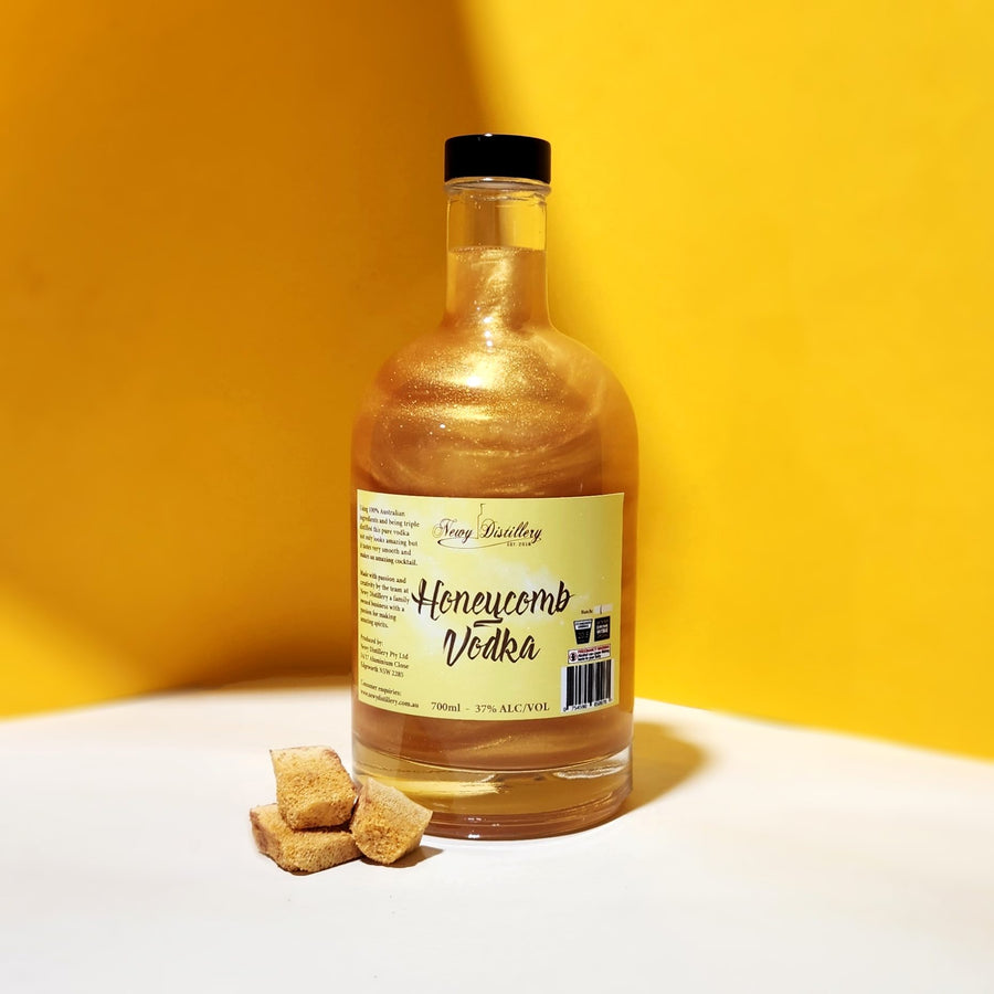 Newy Distillery Honeycomb Vodka. Honeycomb flavoured vodka, with golden shimmer. Bottle on white with yellow background with honeycomb biscuits. Golden vodka.