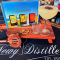 Cocktail kit with a cocktail, glass, and garnish on a stand with 'Newy Distillery' branding.