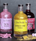 Three bottles of Stewy Distillery vodka with colorful labels on a dark surface.