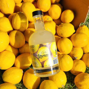 Gin Limoncello by Newy Distillery. 500ml gin limoncello bottle displayed on lemons in fruit crate. 500ml Limoncello Fruit Gin Liqueur.