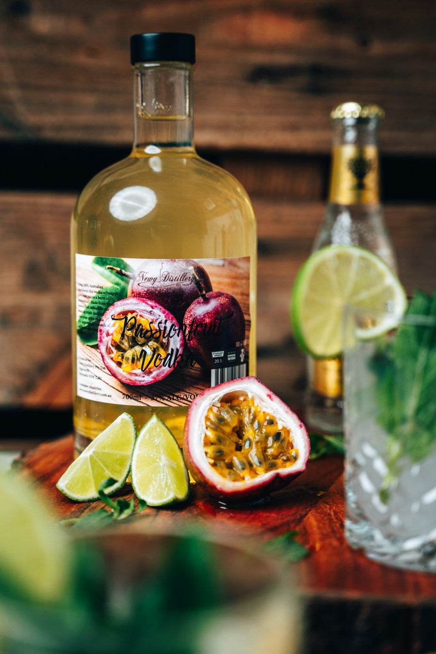 Passionfruit Vodka fruit infused vodka by Newy Distillery. 700ml bottle displayed on wooden bench with fresh passionfruit and lime.