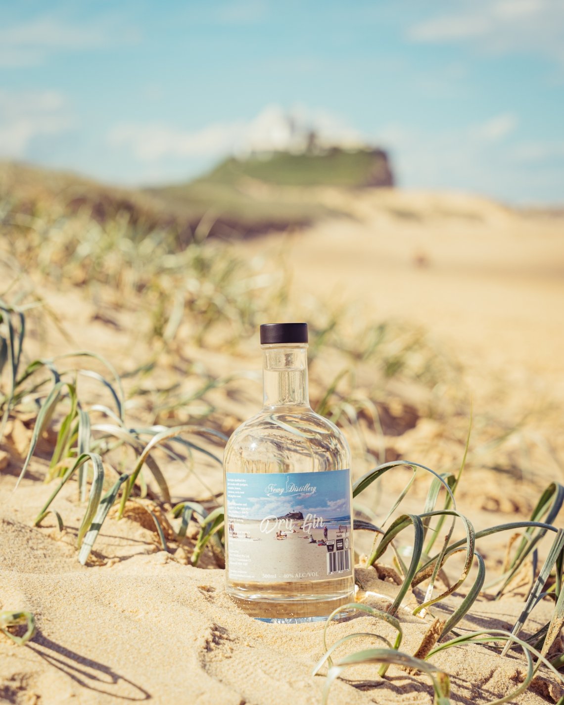 Newy Distillery multi-award Dry Gin 500ml bottle. John Earle label. In the sand at Nobby's beach.