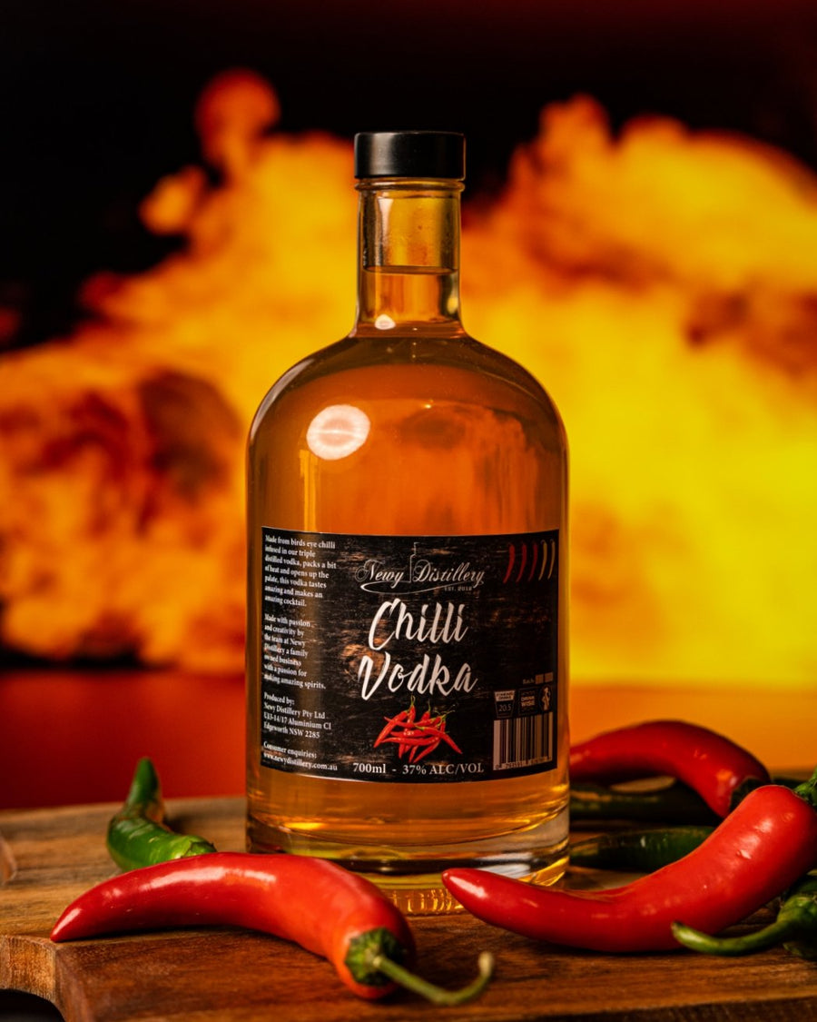 Newy Distillery Chilli infused vodka. 700ml bottle. Displayed next to chillis with fire in the background.